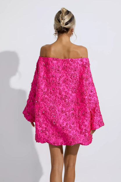 Ervaar de betoverende charme van deze mini-jurk in prachtig roze, met een romantisch bloemendesign en een stijlvolle off-shoulder snit. Deze jurk is een perfecte combinatie van comfort en stijl, ideaal voor diverse gelegenheden waarbij je wilt stralen.