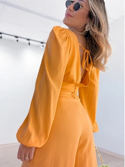 Tweedelige set in trendy oranje kleur. Deze set bestaat uit een top met charmante details en een bijpassende broek, waardoor je moeiteloos stijlvol voor de dag komt. De top heeft lange mouwen en een V-hals voor een trendy uitstraling, terwijl de broek is voorzien van rechte pijpen en een mid-rise taille voor comfort en veelzijdigheid.