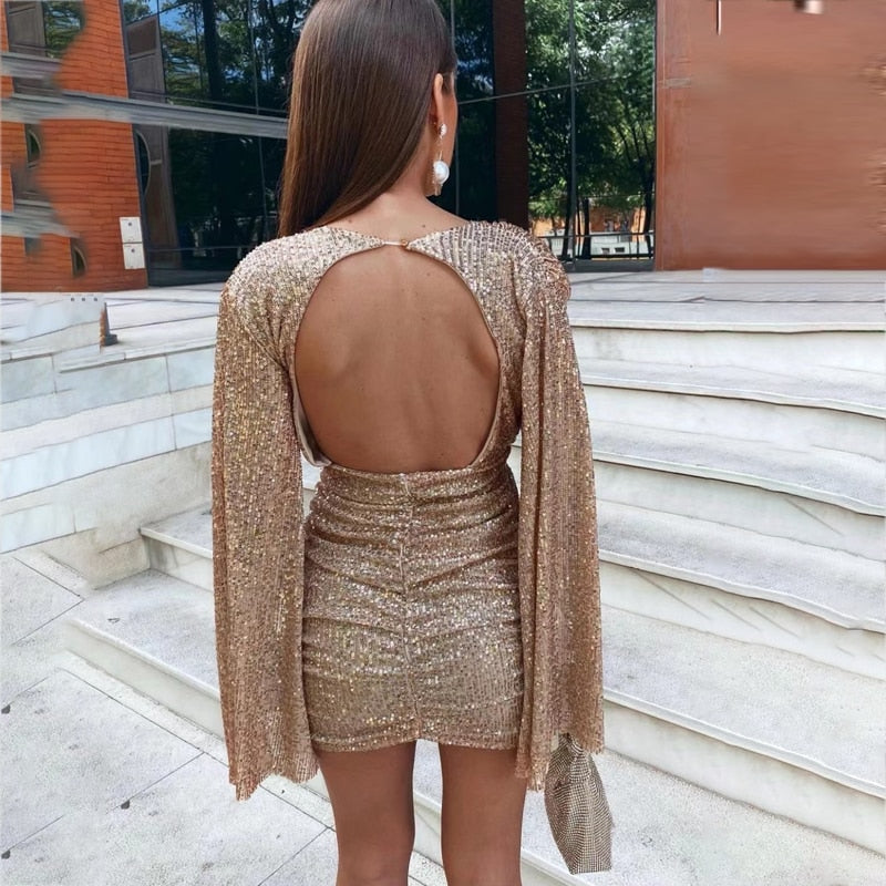 Glitterjurk met V-hals, perfect voor feestelijke gelegenheden. Deze schitterende jurk is voorzien van glinsterende pailletten en heeft elegante wijde cape-mouwen voor een trendy uitstraling. Of je nu een avondje uit gaat of naar een festival, met deze jurk steel je de show. Stijl het met hakken voor een chique look of kies voor een stoere uitstraling met laarzen.